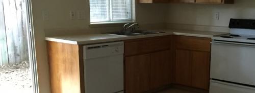 View of the kitchen which has a door leading to the outside walkway.