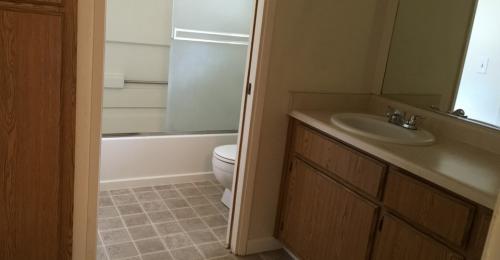 Another bathroom shows light countertops, a sink, a toilet, and shower/tub combo with sliding glass doors.